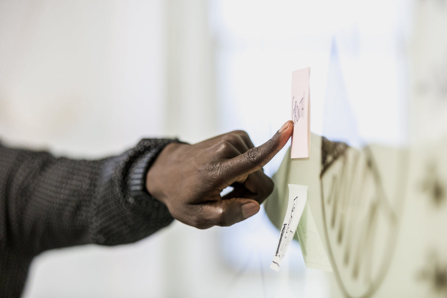 Team member pointing at a post-it board, representing collaboration and planning in Lean leadership.